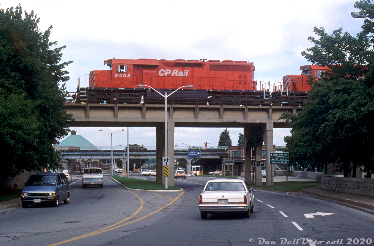 CP SD40 5408 (ex-QNS&L 212, acquired by CP secondhand in 1985) comes into view on the old Michigan Central bridge over traffic on the Niagara Parkway north of Park Street, leading CP 5560, 5563, and 5520 on a westbound entering Canada after crossing over from the states via the giant steel arch bridge over the Niagara River. Notes by Reg indicate this was a reroute due to "Indians", so presumably a local indigenous group blockade somewhere (US or Canada?) forced some extra traffic to detour through downtown Niagara Falls over the old MCRR/CASO line (that had become part of CP's Hamilton Sub in the mid-80's).

The bridge here over the roadway remains today, unused, despite the line being removed through downtown Niagara Falls in 2001. The bridge in the background carries CN's Grimsby Sub from VIA's nearby Niagara Falls station into the US via the Niagara Whirlpool Bridge.

Reg Button photo, Dan Dell'Unto collection slide.