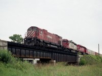 Doesn't look much like a bridge from this angle; and in reality when you are there it doesn't look like much either. Little clearance over the water. But this is the Thames River, and on the right you can see the crossing for Township Road 6. We're just south of the village of Innerkip.
It was nice to catch a big M-636 leading, as they were beginning to be retired and were not very common at the time. ("Un"-retiring of many in 1994 gave us new life on the hunt for these, fortunately.)
So, this is CP 4713 with SOO 6610 and 6614 westbound on a rather dull day of flat grey skies. Nice train.