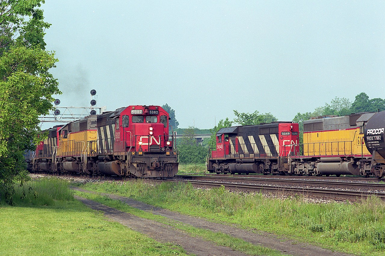 It certainly was a colour show for awhile in 1994 when CN acquired 24 SD40-2s from the Union Pacific. The UP numbers 4090-4102, B4103, 4104 and 4106-4114 came to CN and were temporarily renumbered by changing the first number to a '6' from '4', as seen here; and as they were painted over and slotted in to the CN roster they became 5364-5387 by 1995.
In this image taken at the end of Howard Rd in Aldershot, train #390 has CN 5082, x-UP 6099, CN 5361 and EMD 813 running east, while CN 5048, x-UP 6108 and (out of sight) EMD 763 pulls out of the yard lead. It was an SD paradise around this time as is rather obvious.