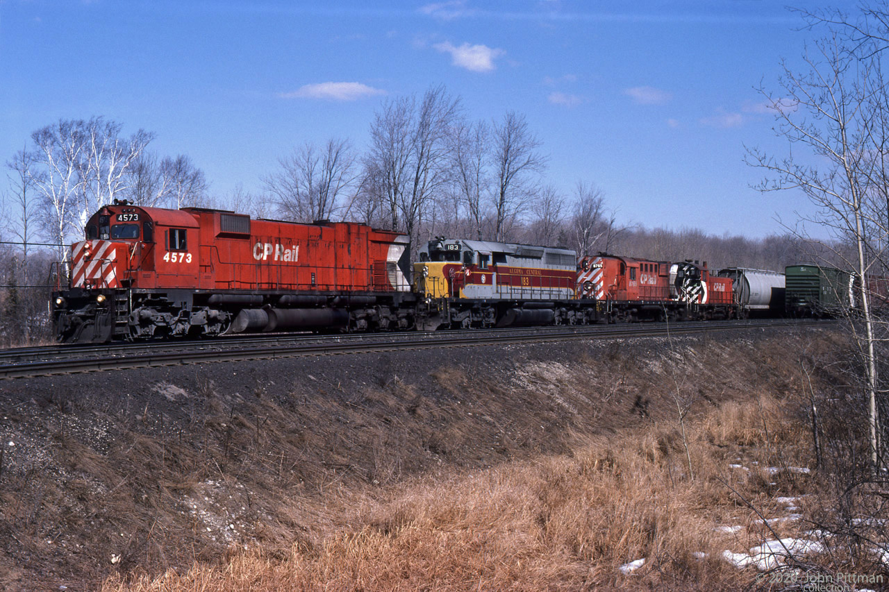 Reg Button caught this very interesting westbound consist in perfect afternoon light in mid-March 1987.
MLW M630 CP 4573 carries a white extra flag on the engineer's side only.
Following are Algoma Central GMD SD40 AC 183, MLW RS-18 CP 8765, and GMD SW1200RS CP 8161.
All CP units wear the then-current wide-stripe multimark scheme.
That same year 1987, CP stopped applying multimarks and black ends during re-painting.