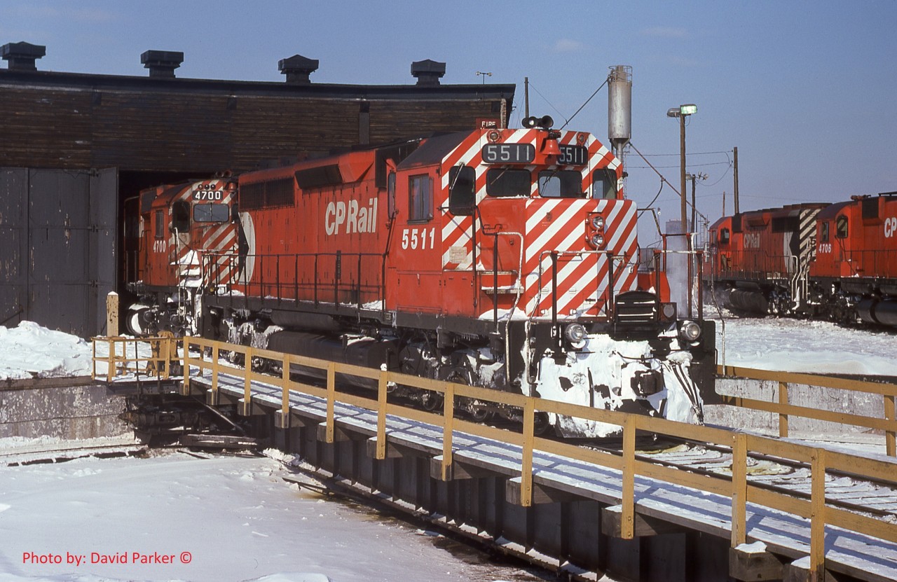 One to cool you down during this hot and humid July 2020.

  CP 5511 is being used to hostle 4700 either into or out of the Windsor roundhouse.  Sometimes during cold weather, the big-un's air starters would freeze up so they would shove them into the house for a warm-up. 
  CP5552-4706 in the background are sitting on the fuel/sand track.