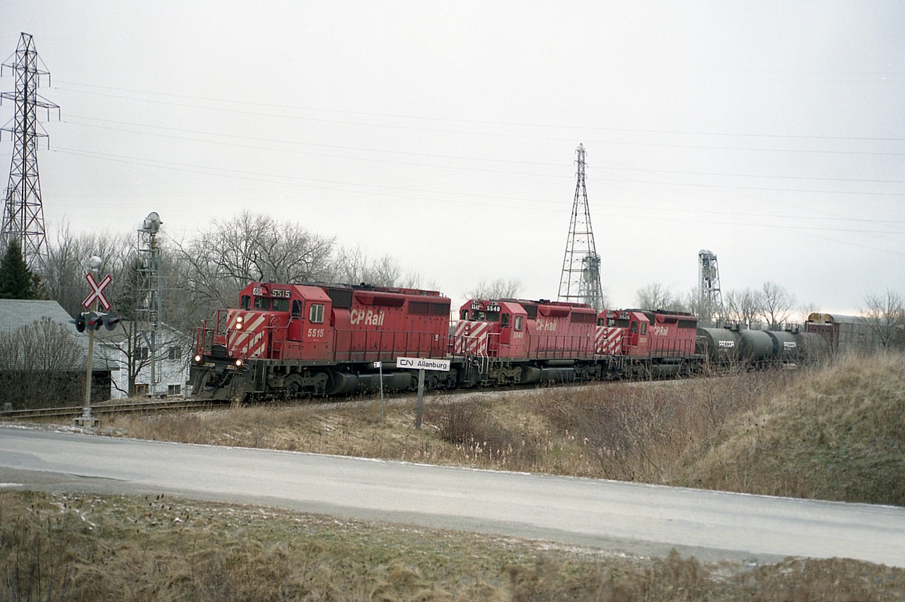 A few years ago I offered up some pictures of a temporary detour, #328 running the Thorold Sub as a shortcut to Port Robinson on account a work block on the Grimsby Sub bridge 6 over Welland Canal. There was a cut-off time, 10AM?? after which trains would have to detour and #328 was quite often all over the place in its' morning schedule.  I caught a handful of these runs; no idea how many their actually were in late 1996 and very early 1997. This one happened to be an all-CP consist, as opposed to the usual, which would have at least one NS unit.
Seen here is CP 5515, 5540 and 5526, an all-SD40 combo about to roll over Barron Rd, immediately before the Port Rob wye. The Hwy 20 bridge over the Welland Canal can be seen in the background.  Today this is just a spur that runs as far as the former Thorold Pulp and Paper plant, and a yard that is currently used for storage. The railroad bridge, #10, over which this train crossed the canal was removed 20 years ago.