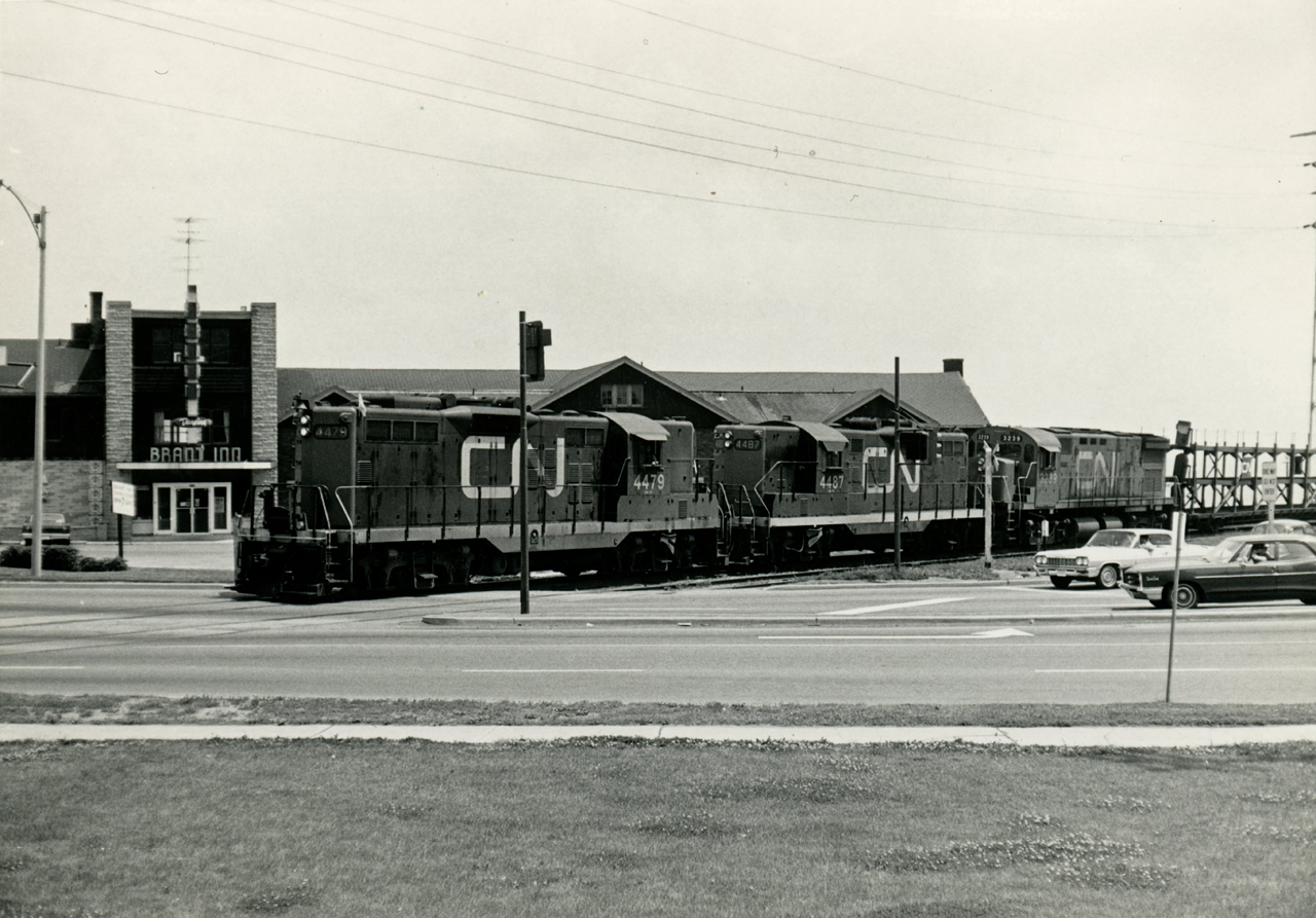 On detour due to the Nash Road Wreck which occurred on July 5, 1968, CN 466 traverses the Beach Sub crossing Lakeshore Road in Burlington with CN 4479, 4487, 3239 for power.  The train is seen passing the Brant Inn, fondly remembered by many for the famous bands and dances hosted there.The original Brant Hotel and Country Club, built in 1900 where the Joseph Brant Memorial Hospital now stands, served as a hotel and club until 1917, when the hotel was expropriated by the Canadian government for use as a military hospital.  The Country Club was renovated into the Brant Inn, continuing as such until a fire on the roof (possibly started by cinders from a passing train) in 1925 burnt the place to the ground.  This second Brant Inn was constructed between 1925-1926 and opened as pictured above, and would be managed by John Murray Anderson through it's peak years with many famous headliners.  Performers included Bert Niosi & Orchestra, Frankie Laine, Sophie Tucker, Louis Armstrong, Ella Fitzgerald, Guy Lombardo, Johnny Mathis, and Liberace.  As the 'Big Band Dances' died out with the times, so too did the Brant Inn.  With health deteriorating, Anderson sold the inn to International Atlas Development and Exploration Ltd. in 1964.  Attempts to keep the place popular continued until 1968, when the company decided to close and demolish the Brant Inn.  The final event would be held on New Years Eve, 1968; demolition began early 1969.  Today this site is home to Spencer Smith Park, named after the former Burlington Horticultural Society president.  The park includes various memorials; to Terry Fox, the Royal Canadian Naval Association Naval Memorial, and a plaque dedicated to the Brant Inn.Locomotive-wise, both GP9's came out of GMD London in 1956.  Leader 4479 would be rebuilt in 1985 to CN 7002 and retired in 2000, finally being sold in 2003 to Pioneer RailCorp retaining it's number.  Trailing geep 4487 would be rebuilt in 1992 to 7048 and continued in CN service until retirement in 2007.  It would be sold in 2014 to the Carolina Costal Railway in North Carolina as their 7048.  MLW C-424 3239, built 1967, would be retired, along with the rest of the fleet, in the mid 1980's.