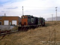 After finishing up their duties further up the line, CN GP9's 4520 and 4515 head south on the southwest leg of CN's GECO Spur (or GECO Branch) in Scarborough, coming around the bend at Milne Ave. crossing while enroute back to the Kingston Sub with a lone caboose in tow. <br><br> As mentioned in a <a href=http://www.railpictures.ca/?attachment_id=34884><b>previous photo</b></a>, the CN's GECO Branch/Spur was constructed to serve the "Golden Mile" area of Scarborough during the post-war industrial boom, as the area formerly inhabited by a World War 2 munitions plant transitioned to domestic manufacturing, and the surrounding farmer's fields were gobbled up by the urban sprawl of the growing Scarborough suburbs. Part of the line was partially built over the old abandoned Canadian Northern right-of-way (that ran north of CN's ex-GTR Kingston Sub). Industrial decline and gentrification in the 90's/2000's resulted in a lot of the factories being redeveloped into neighbourhoods, commercial plazas and townhouses, the loss of rail customers, and today only a portion of the GECO Spur remains to serve the few remaining rail customers. This portion from the Kingston Sub to near the TTC's <a href=http://www.railpictures.ca/?attachment_id=35183><b>Warden Subway Station</b></a> has been removed and the land sold off. <br><br> <i>Mike Mastin photo, Dan Dell'Unto slide collection.</i>