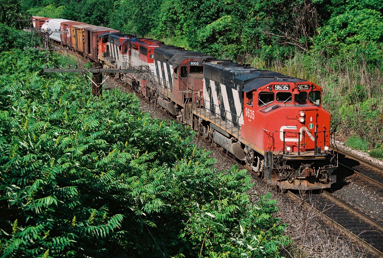 During an early summer morning, four GP40's lead an eastbound CN train approaching the former Snake Road walk bridge (now named Beth Jacob Court). The units included; 9635, 9302, EMDX 201 and 9XXX. GP40 201 is no stranger to the Oakville Subdivision as it had operated as GO Transit 726 prior to becoming part of the Electro-Motive lease fleet. Originally it was built in January 1967 as Chicago Rock Island & Pacific 381.