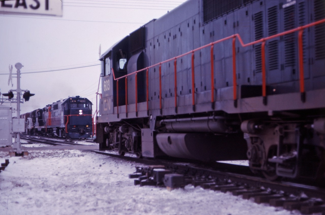 Prior to the start of GO Transit service in May 1967, GO's eight GP40TC units were "broken in" in CN freight service around southern Ontario. In this shot, unit 603 (wearing a CN logo) heads out of Aldershot Yard with an eastbound while the 606 leads a GP9 and RS-18 over the King Road crossing with a westbound freight.