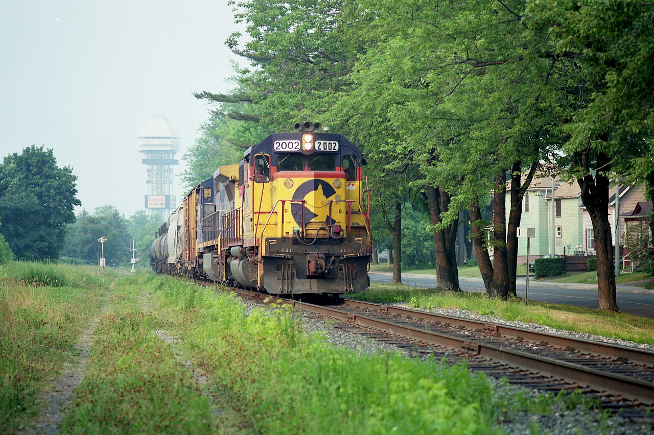 I was surprised to see this train while down in the Falls snooping around because it usually ran much later than the approximate Noon I shot this.
CSX 2002, 7897 heading stateside, having just cleared Clifton Hill and now parallel to Palmer Ave by Mile 1. Interesting to note for todays photographers a sign for Kodak Film on that tower in the old Maple Leaf Village. Yep, we loved it back then.