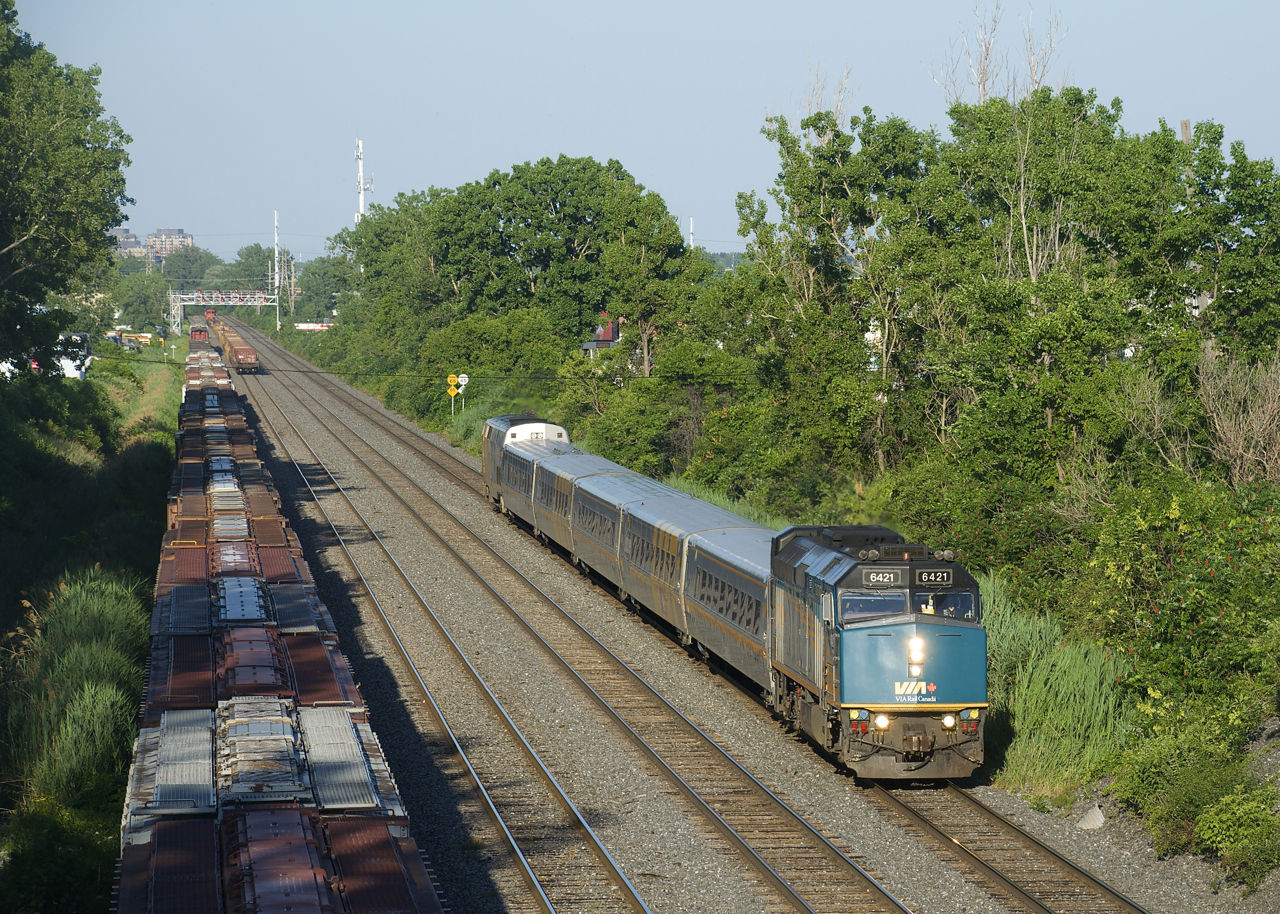 VIA 669 passes a cut of grain cars on a sunny evening.