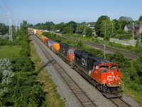 The conductor waves from CN 120 as it approaches MP 14 of CN's Kingston Sub with CN 8944 and CN 5697 power. In a few miles the train will enter Taschereau Yard where cars will be added and the power swapped out for a new set.