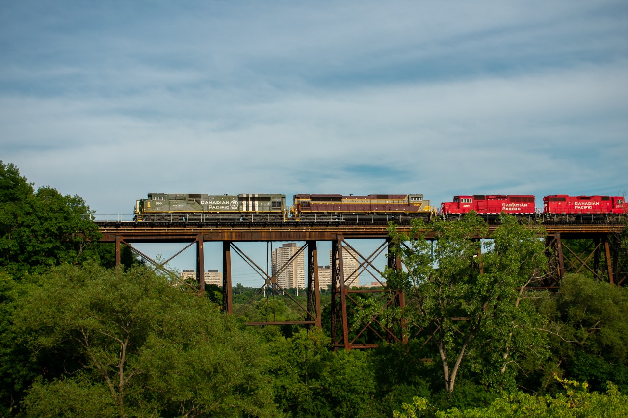 CP 247-25 (likely running as T15 in this photo) crosses what appears to be a singular bridge over the north side of E.T. Seaton Park. This shot taken from Eglinton Avenue between Laird & the DVP has been one I've had my eyes on for a while, especially for afternoon eastbound trains in which the light does not favor. Today I decided to give it a shot, with D-Day unit 6644 leading 7016 (sound familiar?).

 As previously mentioned, this appears to be one solid bridge in the photo, however upon closer inspection you'll realize it's actually 2 completely seperate bridges, sitting around 2 feet apart from each other with alternating supports. I'm not sure why exactly this is but I'd assume it was that one bridge was added whenever the Belleville west of Agincourt as well as the North Toronto was double tracked. This same style is repeated on every valley the tracks cross, with exceptions for the DVP, which is less a bridge and more an arched tunnel built far after the tracks existed, and the valley between Summerhill and Rosedale, which has a ballasted bridge that can accommodate for 3 tracks, as it was once a lead for the North Toronto Station.  

Also visible in this photo, the 2 road units are towing behind 2 yard units, GP20C-ECO 2281, and GP38-2 3042. These engines are the current assigned power to Lambton Yard, and the reason they are seen on this train is because the crew from 247 in some cases will end their shift in Lambton and the yard crew will take care of their switching and then proceed to bring the train the rest of the way to Agincourt. The yard power tags along simply as a taxi basically so once the crew has finished dropping the train in Agincourt they have an easy and fast way to get back to Lambton. This would be the reason as well that they'd be running as T15, since it is technically a yard transfer with a yard crew after Lambton.