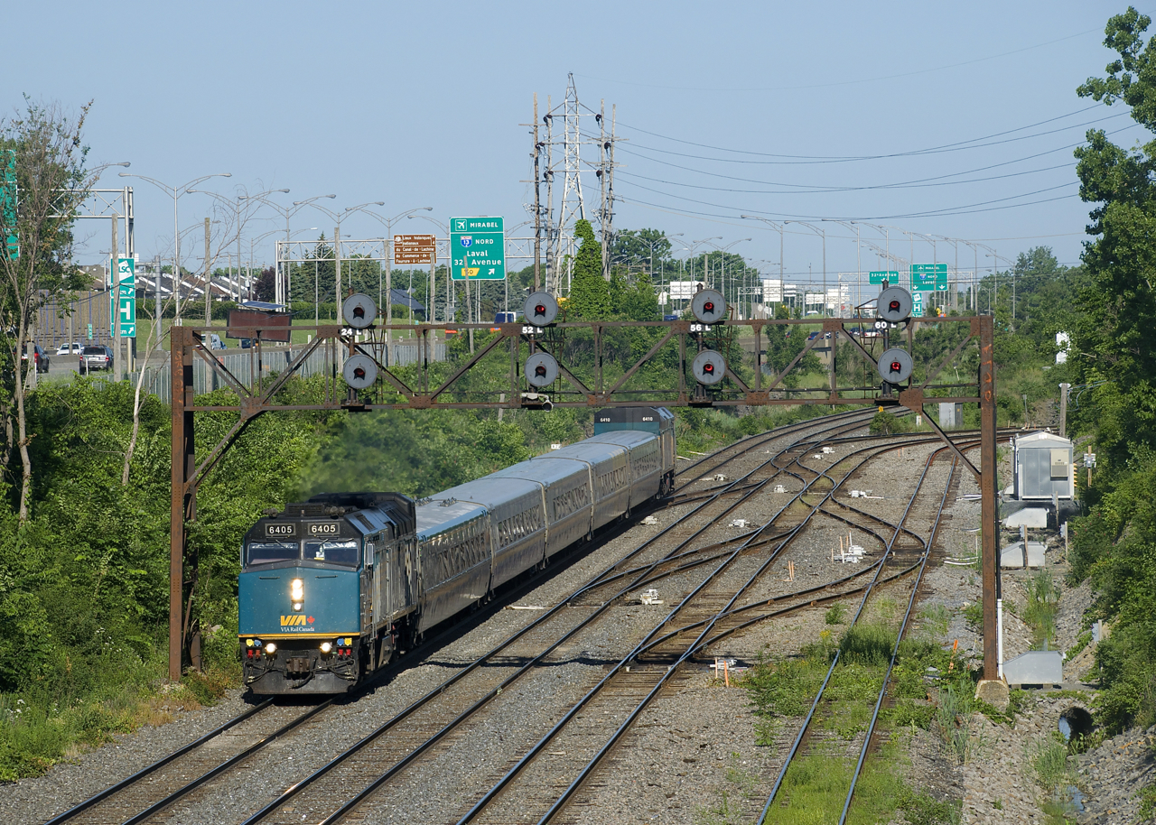 VIA 22 has VIA 6405 and VIA 6410 bookending five LRC cars as it passes underneath a signal bridge near Taschereau Yard.