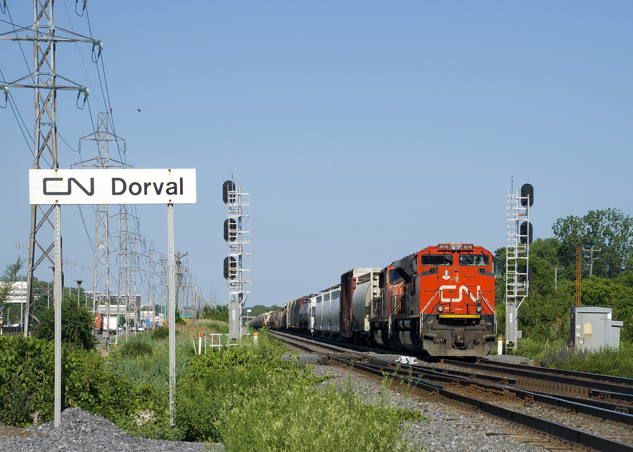 CN 8018 and CN 5760 are the head end power on a 165-car CN 322 (with CN 8944 and CN 2320 assisting mid-train) as it passes the Dorval station sign not too longer after meeting CN 369.