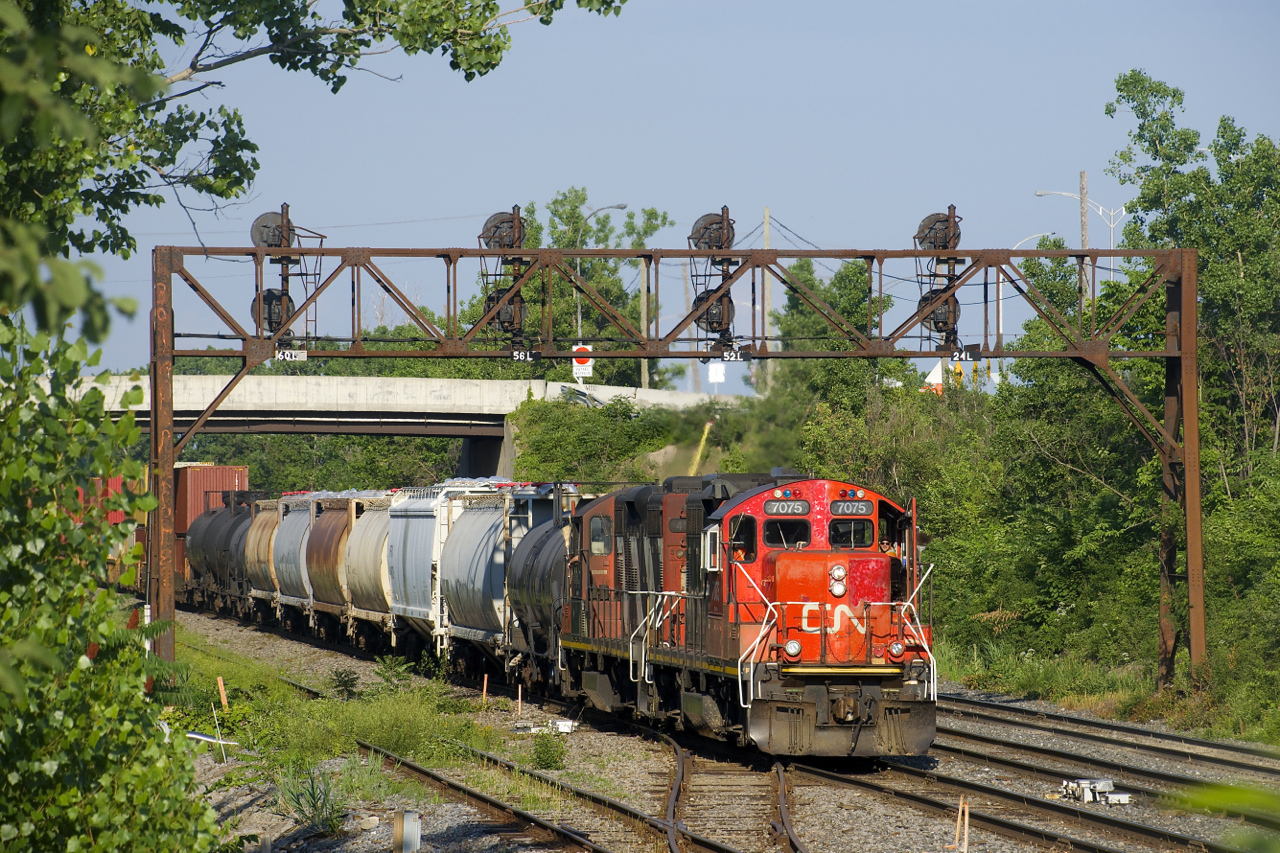 After waiting for an eastbound to leave Taschereau Yard, CN 596 with traffic from the Port of Montreal is about to enter the yard with GP9's CN 7075 & CN 4141 for power.