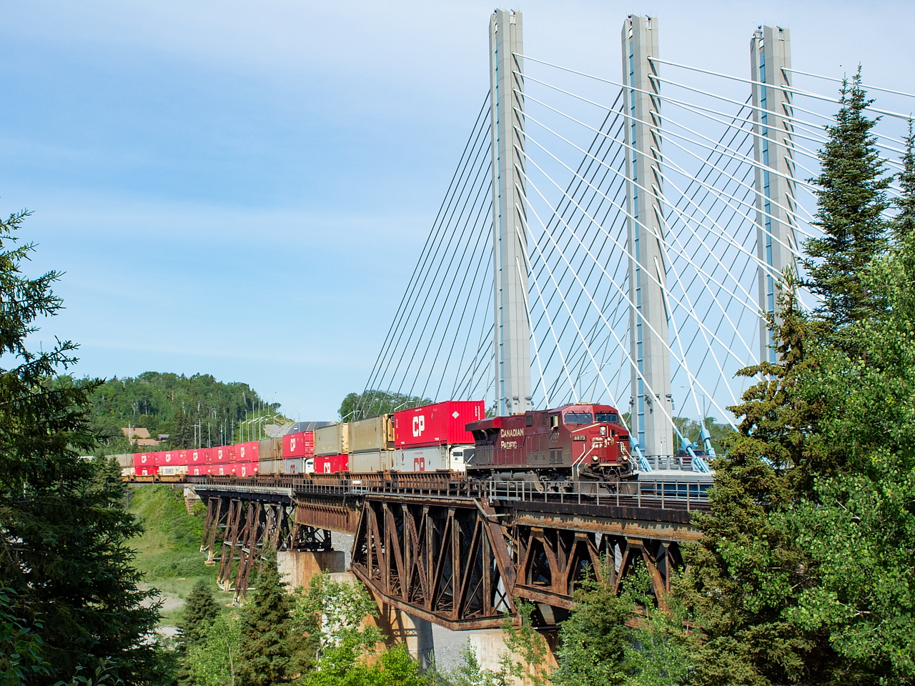 CP 8873 leads CP 100 across the Nipigon River and alongside the Trans Canada Highway, which you can also see peaking out from behind the train at the top of the hill.