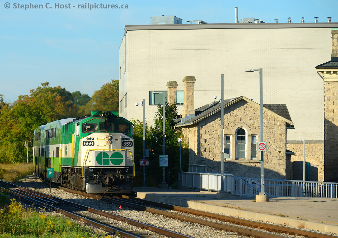 The last Eastbound GO train of the day is passing new and old city hall in downtown Guelph. The old city hall with the old stone secondary building seen was built in 1856-7. The new was built around 2008-2009.