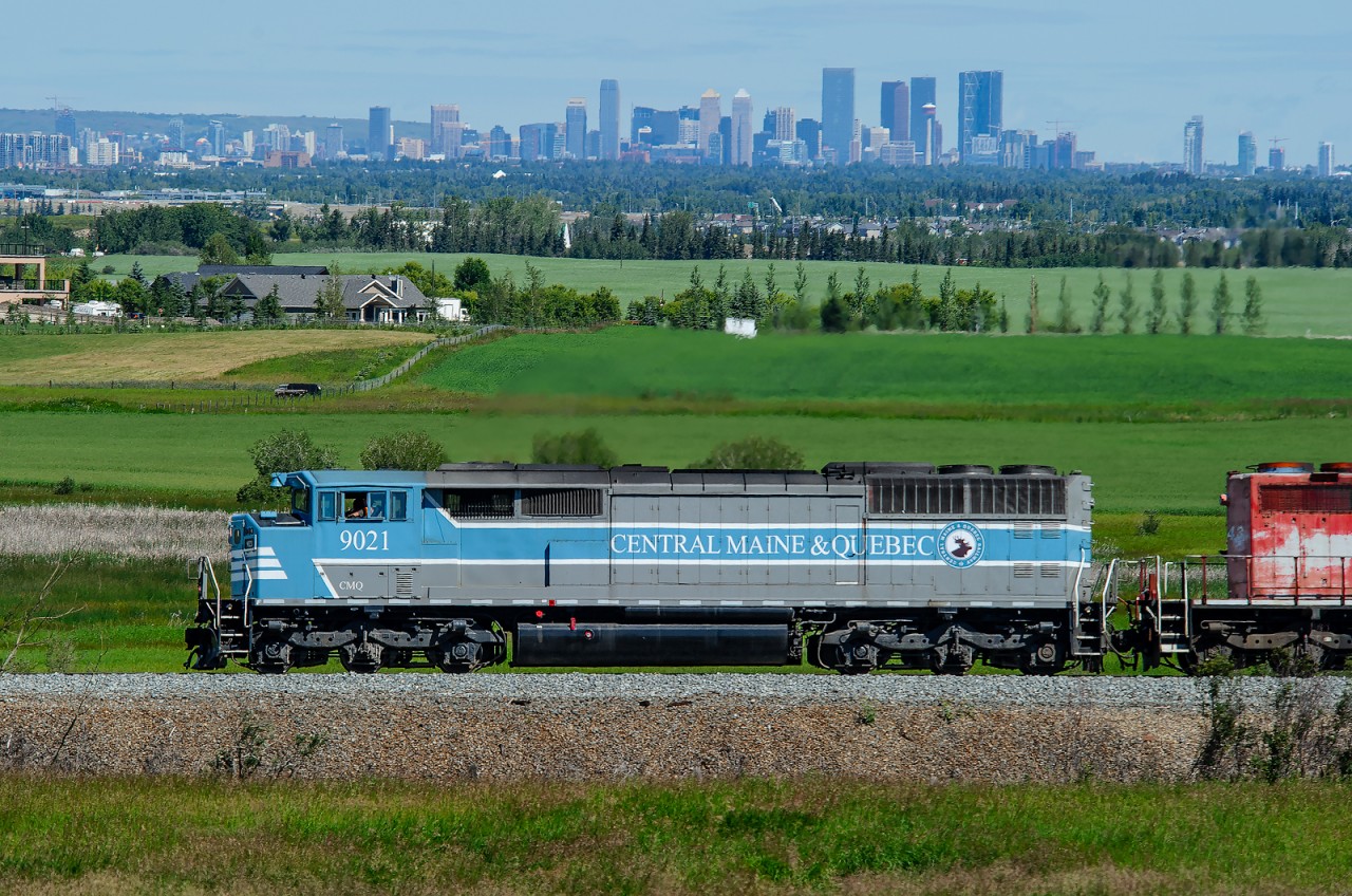The City of Calgary in the distance does not belong to either Maine or Quebec, yet we see Central Maine and Quebec SD40-2F 9021 heading towards it with a loaded ballast train in tow. 2020 - you're crazy.