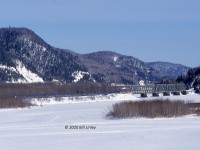 On Tuesday, March 7, 2005, VIA's OCEAN, Train 14, departs Matapedia, Quebec en route from Montreal, Quebec to Halifax, Nova Scotia.  The train is just about to cross the Restigouche River and enter the province of New Brunswick.<br><br>F40PH-2 locomotives 6416 and 6426 lead baggage 8619, coaches 8139 and 8127, Skyline 8505, diner Louise, Chateau sleepers Laval, Marquette, Papineau, Viger, Radisson, Jolliet and Laurentide Park.  During the station stop at Matapedia, the crew had separated the CHALEUR from the head end of the OCEAN.  Gaspe-bound Train 16 included engine 6427 and cars 8618 8108 8527 Chateau Iberville and Chateau Montcalm.<br><br>Railfan friend and future son-in-law, Steven Dickie, and I had driven from his home in Fredericton to capture this view as it would usually be dark as the OCEAN departed Matapedia.    The train departed in the early afternoon as it had been restricted to 10 mph on sections of the Montmagny and Mont Joli Subdivisions due to a minor earthquake.   We elected to chase the eastbound OCEAN so the Gaspe chase culminating in a delightful meal at the Adams Restaurant would have to wait for another day.
