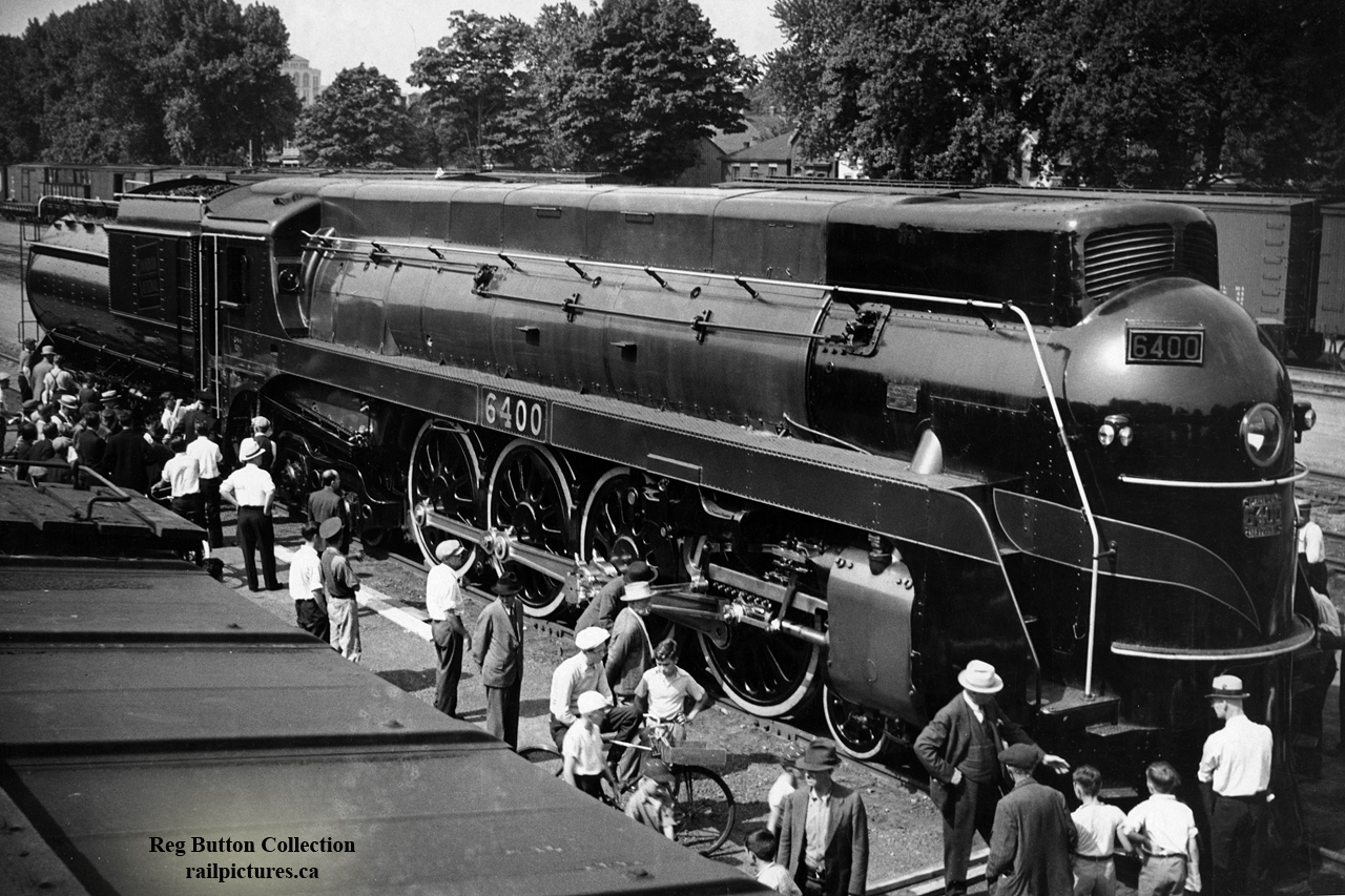 Newly built CNR 6400, one of five U-4-a 4-8-4 locomotives built by MLW in 1936, is seen on public display at the Ferguson Avenue freight shed in Hamilton.  The streamlined Confederations were used in Ontario/Quebec passenger service until their retirements in 1960/1961.  CN 6400 is the sole survivor of the fleet, currently on display at the Canada Science & Technology Museum along with various other pieces of railway equipment.  Shortly after construction it was used as an excursion locomotive out of Laprairie, Quebec in 1936 for the centennial celebrations of Canada's first railway; the Champlain & St. Lawrence, having commenced operation on July 21, 1836 with locomotive Dorchester built in England at Newcastle upon Tyne.  6400 would shed it's olive green paint for Royal Blue as it and six other Canadian locomotives would pull the Royal Train carrying King George VI, Queen Elizabeth II, throughout Canada in May and June, 1939 in what would be the first visit to Canada by reigning Monarchs.  1939 would also see 6400 still in royal blue make a trip to New York as an exhibit in the "World of Tomorrow" display at the New York World's Fair.  After just over two decades in service, 6400 would be retired in 1960, ending up in a scrap line at the London Reclamation Yard before being set aside by CNR for preservation as part of the Museum Train; also known as the "Journey into Yesterday".  It would continue in museum train service as well as appearing at other event displays until Canada's centennial celebrations in 1967, when the Museum of Science and Technology in Ottawa would open.  6400 and a number of other locomotives were pushed inside for permanent display.The CNR Museum Train began in 1953 with CN 40, a 4-4-0 built for the Grand Trunk in 1872, CN 247, a saddle tank 0-6-0 built in 1894 for Grand Trunk, and CN 713, a 2-6-0 built for Grand Trunk in 1900 and a selection of vintage wooden equipment dating as far back as 1859.  The train toured Canada highlighting railway heritage and the railway's contributions to the country until 1967, Canada's Centennial, when the National museum of Science and Technology opened in Ottawa.  The Museum train was retired and put on display.CNR's Ferguson Avenue freight sheds, the sixth largest in Canada, stretched north-south from Barton Street south to Canon Street.  One of the customers using the shed was E.T. Wright & Co., a tinware company eventually manufacturing many types of lanterns, including for use by Canadian railways. From the small yard beside the shed, switchers could run over to the N&NW spur without crossing the Grimsby Sub by using an underpass of Barton Street and the Grimsby, reconnecting to the N&NW spur around the intersection of Wellington Street North and Simcoe Street East.Through the trees at upper left the addition to the Royal Connaught Hotel can be seen at the corner of King Street East and John Street South.  The Royal Connaught, built in 1914-1916 by Pigott Construction, and named after then Governer General of Canada, Prince Arthur, Duke of Connaught (and Strathearn,) has stood for over 100 years, now serving as the Residences of the Royal Connaught Condominiums after the hotel closed in 2008.  This hotel would not be the only structure named after the Governer General, as the Canadian Pacific Railway's 5.02 mile long Selkirk Tunnel on the Roger's Pass line in British Columbia, opened by the Duke of Connaught in 1916, would be renamed the Connaught Tunnel a few weeks later after opening.