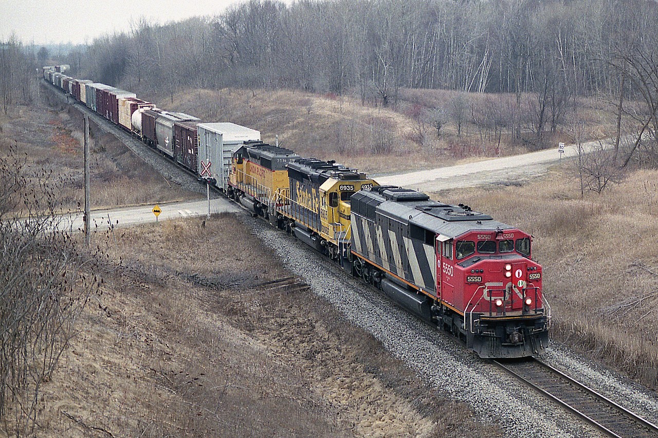 Up on the Golf Course Bridge (it is off season) in order to grab a shot of CN #393 heading west; and it was a pleasant surprise to see some interesting power. Up front is CN 5550, Santa Fe (BNSF) 6945 and UP 3586. The view shows the train crossing over 10 Side Rd on the east side of Hwy 25. CN #393 was held at Burlington West for traffic on the Oakville sub., so managed to catch up to it and grab another photo. It was well worth it.