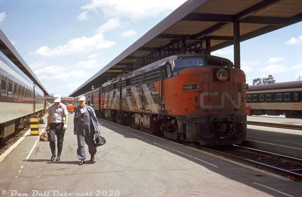 A pair of MLW-built FPA4's lead by CN 6763 rest along the platforms at Ottawa Station, as their head-end crew walks away from the power after finishing their run (probably on a Toronto-Ottawa train). Further back, an attendant can be seen handling baggage out of the trailing baggage car. On the left, one of CN's little MLW switchers (probably an S4 in the 8030-series) handles the consist of the train in the adjacent track. 

Less than a decade old, this "new" Ottawa station off Trembley Road was the result of a move to relocate Ottawa's main Union Station from its previous downtown location (along the Rideau Canal and opposite Chateau Laurier) to a new one further away. A new building was built and opened in August 1966, and the old station downtown was closed and the trackage along the Rideau Canal accessing it were removed, all part of an early urban renewal effort aimed at relocating the trains out of the downtown Ottawa area.

Built in 1959, CN FPA4 6763 spent only a few years in its original yellow and green livery before being repainted into the sharp zebra stripe livery under the new corporate "CN" image of the early 1960's, which it wore until being repainted in VIA colours sometime around 1977. After the FPA4/FPB4 fleet was retired from VIA in the late 80's, 6763 and seven other VIA FA/FB's were purchased by the Windsor & Hantsport for parts in 1995. All ended up being resold, and 6763 under several owners made its way to the Danbury Railroad Museum, but is presently stored in old faded VIA colours in the deadline on the Delaware Lackawanna Railway in Scranton PA (the museum has two other FPA4/FPB4 units restored in the CN 1960's livery).

Original photographer unknown, Dan Dell'Unto collection slide (processing date stamped July-1973, but believed to be a Summer 1972 image developed late)
