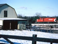 The last CP train to operate to Guelph on the Goderich Subdivision approaches the hamlet of Arkell. GP9u 1614 and one hopper are passing a barn along Watson Road where even the animals wouldn't dare venture outside due to the frigid temperatures that day. 