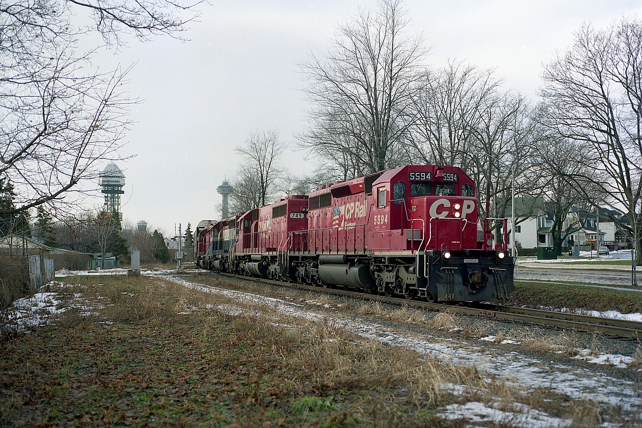 Seen in this image, CP's #558 heading toward the states; a mile to do as it passes over Eastwood Cres along the line that parallels Palmer Av for a stretch. Line is gone now, and is a walking/biking trail for some of its' length. Power is CP 5994, 749, HLCX 6206, CP 5674. The HLCX is former B.C. Rail. The towers of Clifton Hill tourist mecca can be seen in the background.