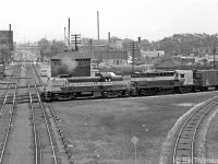 Canadian Pacific RS2 8406 and RS18 8745 lead a freight northbound over the West Toronto diamonds, passing the old West Toronto Junction interlocking tower as they cross over from the Galt Sub (via the Galt-MacTier connecting track) to the MacTier Sub. The bisecting tracks they are about to cross are for CP's North Toronto Sub, heading east through midtown Toronto to Leaside, and further points east on the Bellville Sub. This photo offers a better view of the old grade crossing tower in the distance at Osler Street, near where the MacTier Sub split off to the north.<br><br>CP had just four MLW-built RS2 units, 8405-8408, which were overshadowed by their well-known Alco RS2's (8400-8404, that lasted into the 1980's on CP's lines in the US) and the fleet of more populous MLW RS3 (8426-8461). Unlike the Alco-built units, 8405-8408 all had MU, so were often seen operating in mainline freight service mixed with other units. 8405 & 8408 were traded in to MLW for C424's in 1965, while 8406 suffered fire-damage and was retired in 1969. 8407 lasted through the 1970's in yard service out of St. Luc in Montreal, until retirement in 1982. By that time, CP's six remaining units were some of the final RS2's in operation.<br><br><i><b>More at West Toronto:</b></i><br> A view inside the interlocking tower: <b><a href=http://www.railpictures.ca/?attachment_id=28987>http://www.railpictures.ca/?attachment_id=28987</a></b><br>CN steam power in the winter: <a href=http://www.railpictures.ca/?attachment_id=16093><b>http://www.railpictures.ca/?attachment_id=16093</b></a><br>CP 8917 "Train Master" in transfer service: <a href=http://www.railpictures.ca/?attachment_id=15874><b>http://www.railpictures.ca/?attachment_id=15874</b></a><br> NYC power on the Starlight heading westbound by Osler Street: <a href=http://www.railpictures.ca/?attachment_id=15002><b>http://www.railpictures.ca/?attachment_id=15002</b></a>