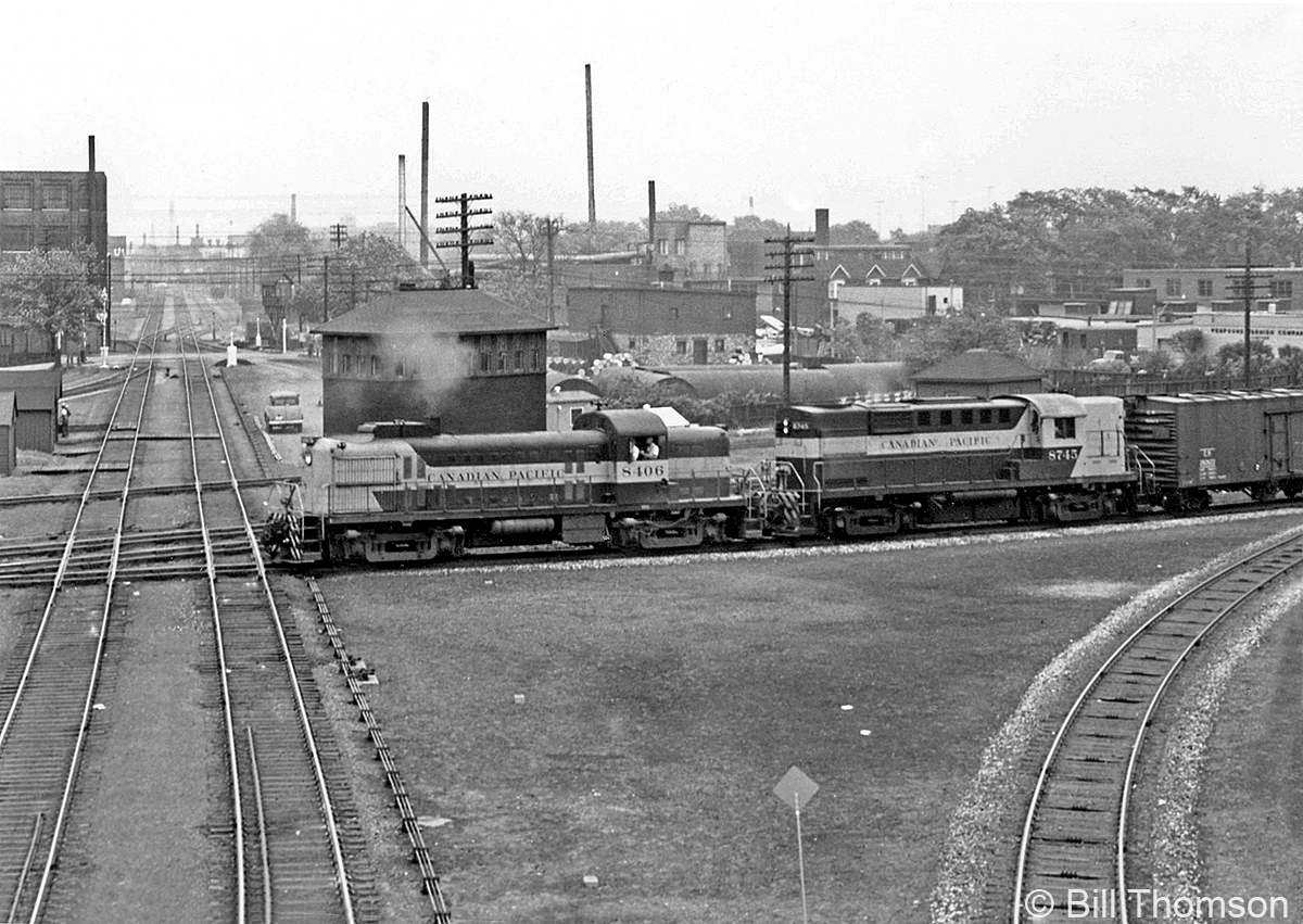 Canadian Pacific RS2 8406 and RS18 8745 lead a freight northbound over the West Toronto diamonds, passing the old West Toronto Junction interlocking tower as they cross over from the Galt Sub via the Galt-MacTier connecting track to the MacTier Sub. The bisecting tracks they are about to cross are for CP's North Toronto Sub, heading east through midtown Toronto to Leaside, and points east on the Bellville Sub. This view offers a better view of the old grade crossing tower in the distance at Osler Street, near where the MacTier Sub split off to the north.CP had just four MLW-built RS2 units, 8405-8408, which were overshadowed by their well-known Alco RS2's (8400-8404, that lasted into the 1980's on CP's lines in the US) and the fleet of more populous MLW RS3 (8426-8461). Unlike the Alco-built units, 8405-8408 all had MU, so were often seen operating on in mainline freight service mixed with other units. 8405 & 8408 were traded in to MLW for C424's in 1965, while 8406 suffered fire-damage and was retired in 1969. 8407 lasted through the 1970's in yard service out of St. Luc in Montreal, until retirement in 1982. By that time, CP's six remaining units were some of the final RS2's in operation.More at West Toronto: A view inside the interlocking tower: http://www.railpictures.ca/?attachment_id=28987CN steam power in the winter: http://www.railpictures.ca/?attachment_id=16093CP 8917 "Train Master" in transfer service: http://www.railpictures.ca/?attachment_id=15874 NYC power on the Starlight heading westbound by Osler Street:http://www.railpictures.ca/?attachment_id=15002
