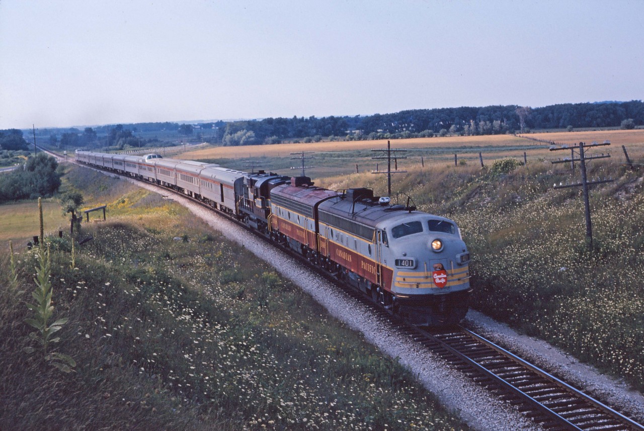 Having departed Sudbury at 11:15, CP's The Canadian is just clearing the crossing of County Road 10 as it approaches Beeton in the summer of 1962. The 12 car train is led by FP7 1401, F7B 1918, and RS10 8572 (if I'm reading the numbers correctly). The Canadian was re-routed over CN's Bala sub when took over in 1978...