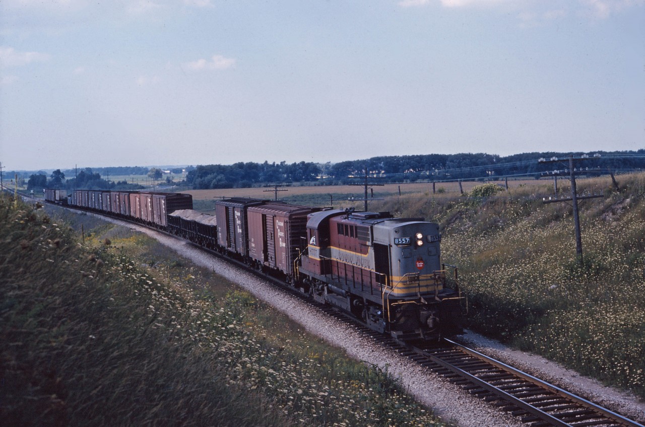 Heading south on the MacTier Sub, a freight train powered by steam generator equipped RS10 8557 approaches the north siding switch at Beeton. (Note the "beaver" crest on the nose, the large combined fuel/water tank, and the exhaust vents on the short hood--spotting features for a dual service road switcher.) In this pre-scanner era, we don't positively know the train number but a 1963 employee timetable suggests that it is No. 86, a daily scheduled train whose schedule began at Medonte and, according to the timetable, was supposed to be overtaken by No. 12, The Canadian, at Midhurst--30 miles to the north--at 3:25 PM. In the early 1960s, the timetable provided 4 northward second class schedules for dispatcher use (Numbers 901, 953, 955, and 965), 2 southward second class schedules (Nos. 948 and 954), and 5 southward fourth class schedules in a 24 hour period (Nos. 80, 82, 84, 86, and 88). Additional northbound trains would operate as "Extras" or Sections of a schedule. Operation by timetable and train order was a beautiful thing--provided everyone had an accurate watch, properly calculated the times they had to be in the clear, and as long as nothing went wrong!