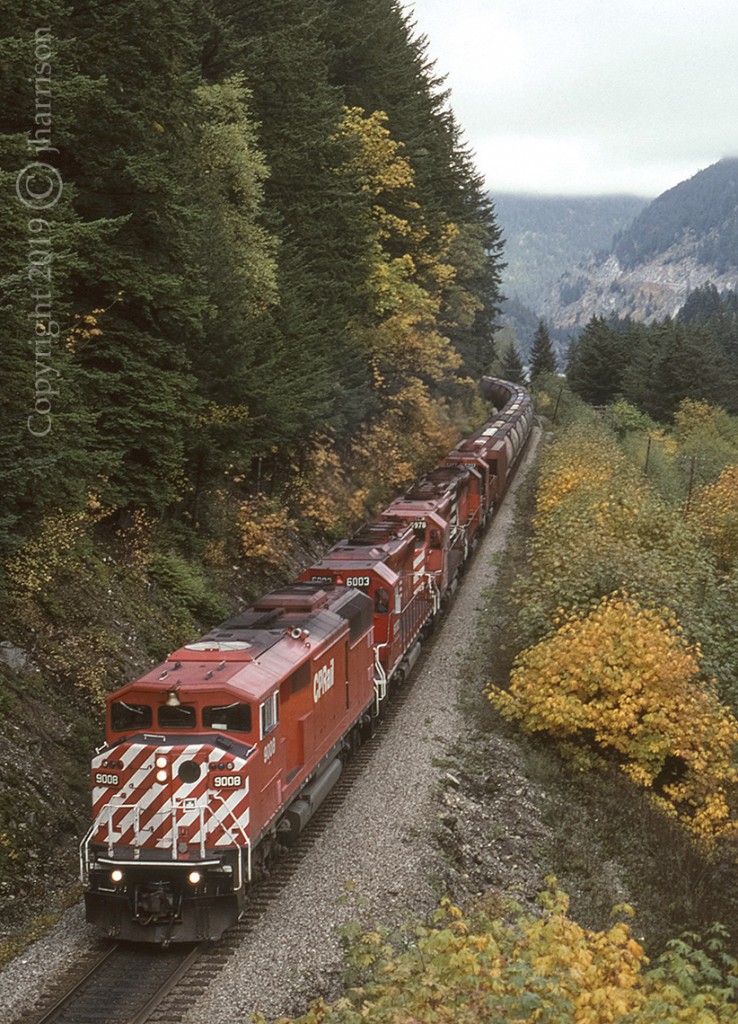 CP 9008 is westbound with the 6003 5978 5171 and 5707 trailing as they approach the village of Spuzzum on CPs Cascade Sub. This shot was taken from the Alexandria Bridge which crosses the Fraser River and both CP and CN lines at this location. This shot is no longer possible. The trees have grown up and over the tracks creating a tunnel effect. Mid train RCUs this day were CP 6057 and 5942.