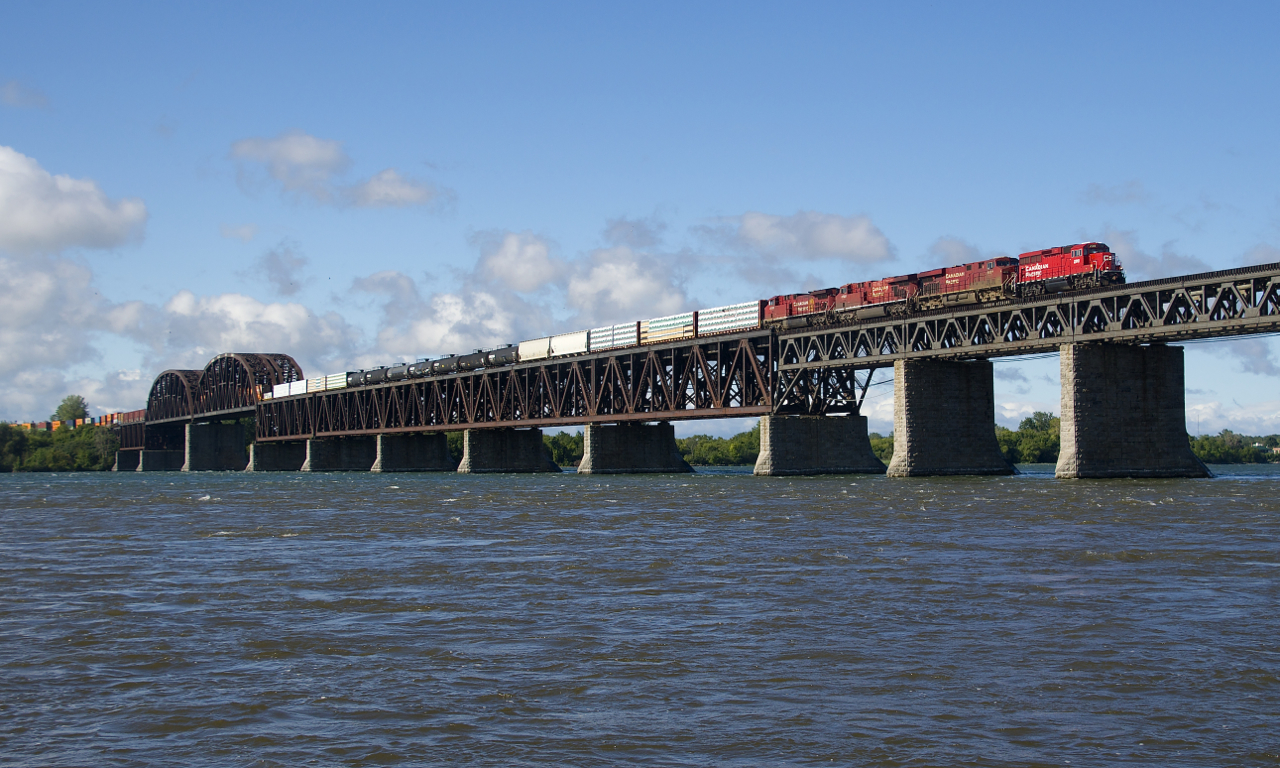 A GP20C-ECO is leading three GE's as a long CP 251 crosses the St. Lawrence river with mixed freight followed by intermodal traffic. Unit numbers are CP 2318, CP 8873, CP 8720 & CP 8136.