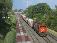 A 44-car CN 323 has CN 8014 and CN 5668 for power as it approaches Taschereau Yard. Grain cars can be seen on the three other tracks of CN's Montreal Sub. Parked grain cars are at far left on the transfer track and receding into the distance are the tail ends of CN 596 with a short transfer of grain cars on the freight track and grain train CN 878 at far right on the south track. 