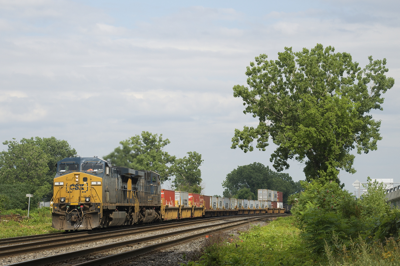 A low-numbered AC4400CW leads CN 327 as it passes through Dorval with CSXT 9 & CSXT 587 for power. Up front are 16 intermodal platforms.