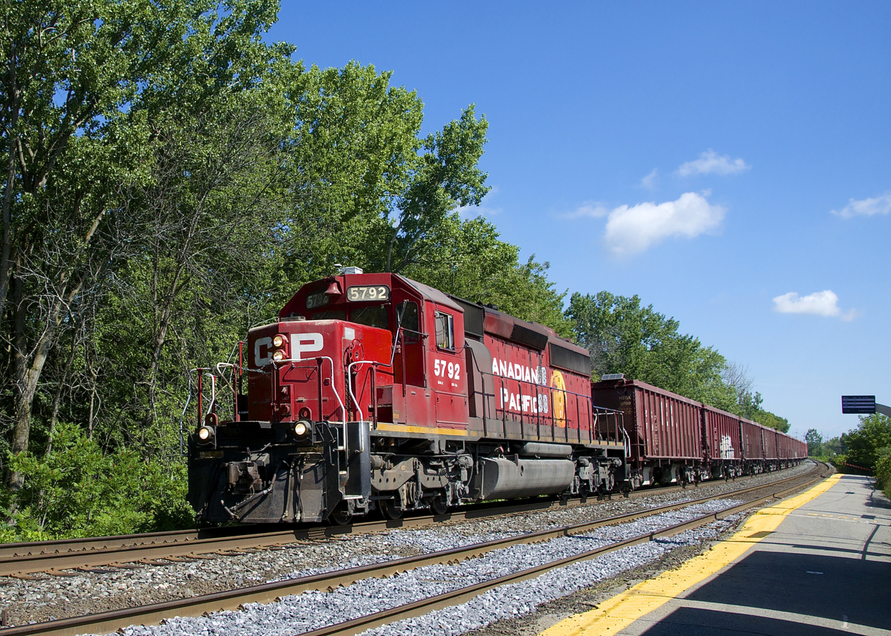 A CP ballast train powered by CP 5792 is passing the Île-Perrot Station. CP 5792 is one of the few CP SD40-2's to have a beaver on the long hood.