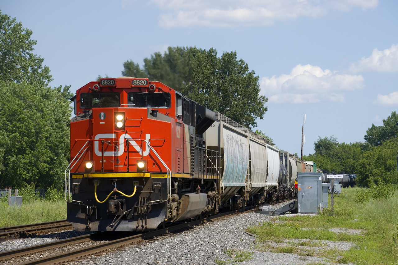 A 95-car CN 305 rounds a corner with CN 8820 up front and CN 8102 mid-train.