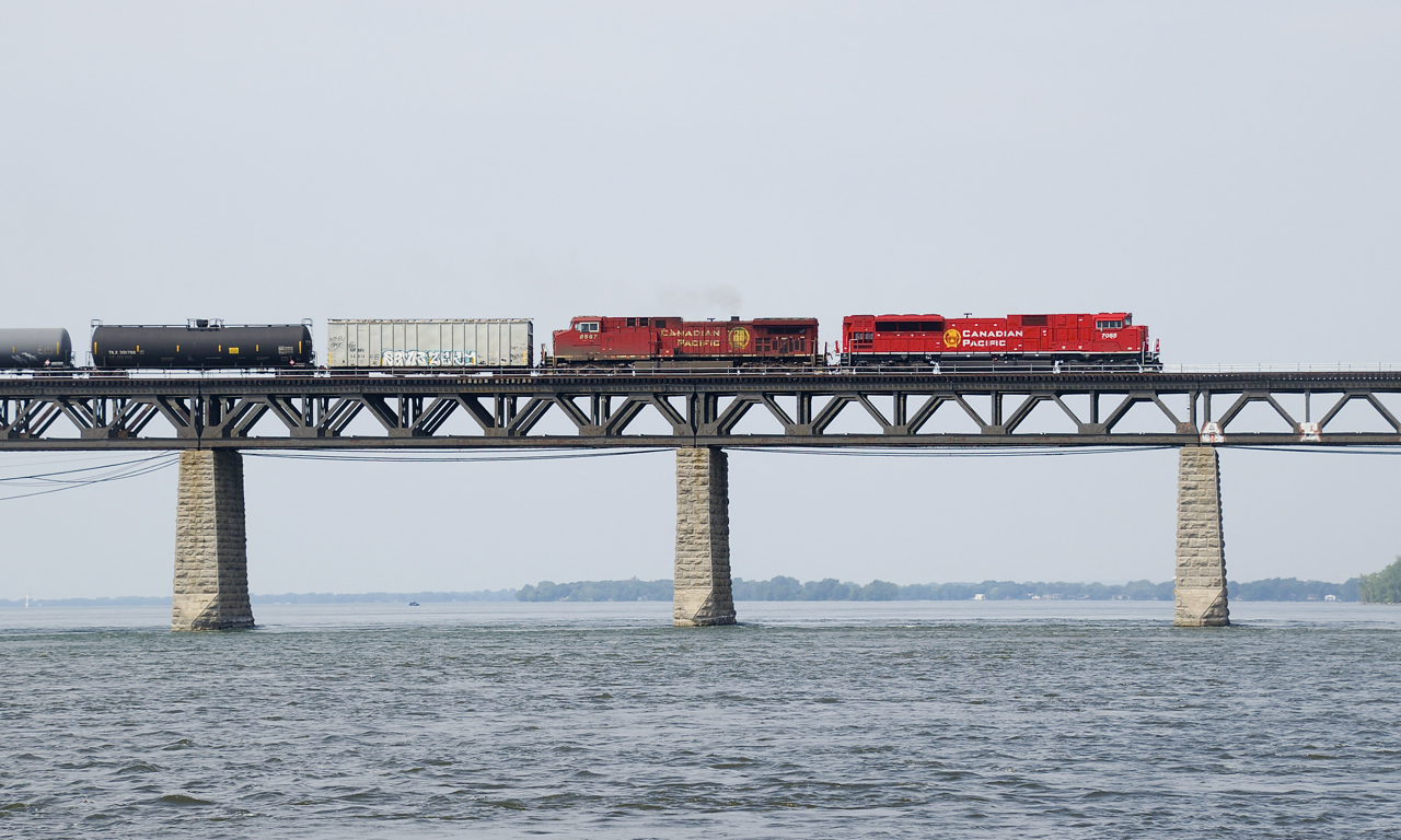Freshly rebuilt CP 7055 and grungey CP 8567 present a contrast in appearance as they lead empty ethanol train CP 651 over the St. Lawrence River on a muggy morning.