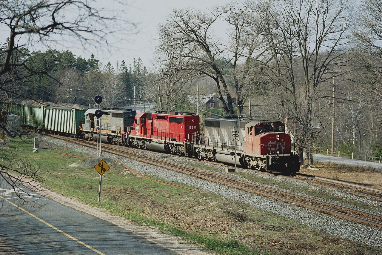 Dock Siding is where Road #612 thru MacTier n/b comes out at main Hwy 69, south of Parry Sound. Hwy 69 can be seen on the right, and 612 on the left in the photo. And train #336 south is taking the siding. What is interesting about this shot is the middle unit.
Back in 1996 CN took over the CP haul contract from Ontario Hydro, which involved a coal run from Beinfait, SK to Thunder Bay. Included in the deal came eleven of a group of CP SD40-2s that were captive to this operation.
They were slotted on CN as 5388-5398. (CP kept the other 5 of the 16 involved). Highly visible to the fans on account their bright red paint; by the time I shot this image in early 2001 the CN 5391 pictured here was the last one remaining. The others were actually sold back to CP in 2000. The CN 5391 (former CP 5782) 
soldiered on until retirement in 2008.
Image shows CN 5274, 5391 and GCFX 6069 (Connell Finance Co) formerly CN 5170..rebuilt and leased to CN.