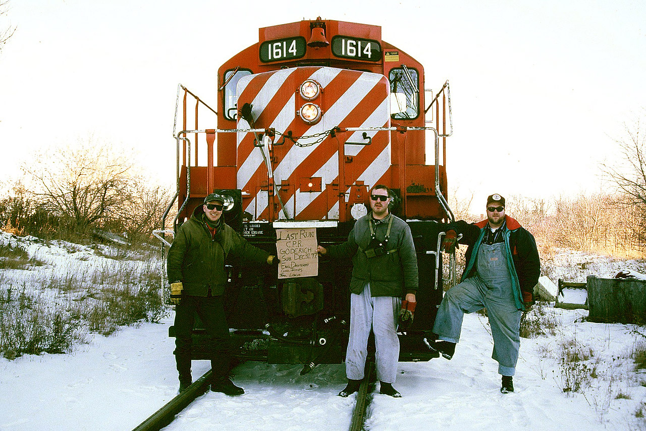 The friendly crew assigned to the last Canadian Pacific train to Guelph on the Goderich Subdivision pauses for some photos with a homemade sign in front of GP9u 1614 on the spur to the Owens Corning plant. From left to right; trainman Ray Lokun, conductor J. James and engineer Kevin Dmyterko.