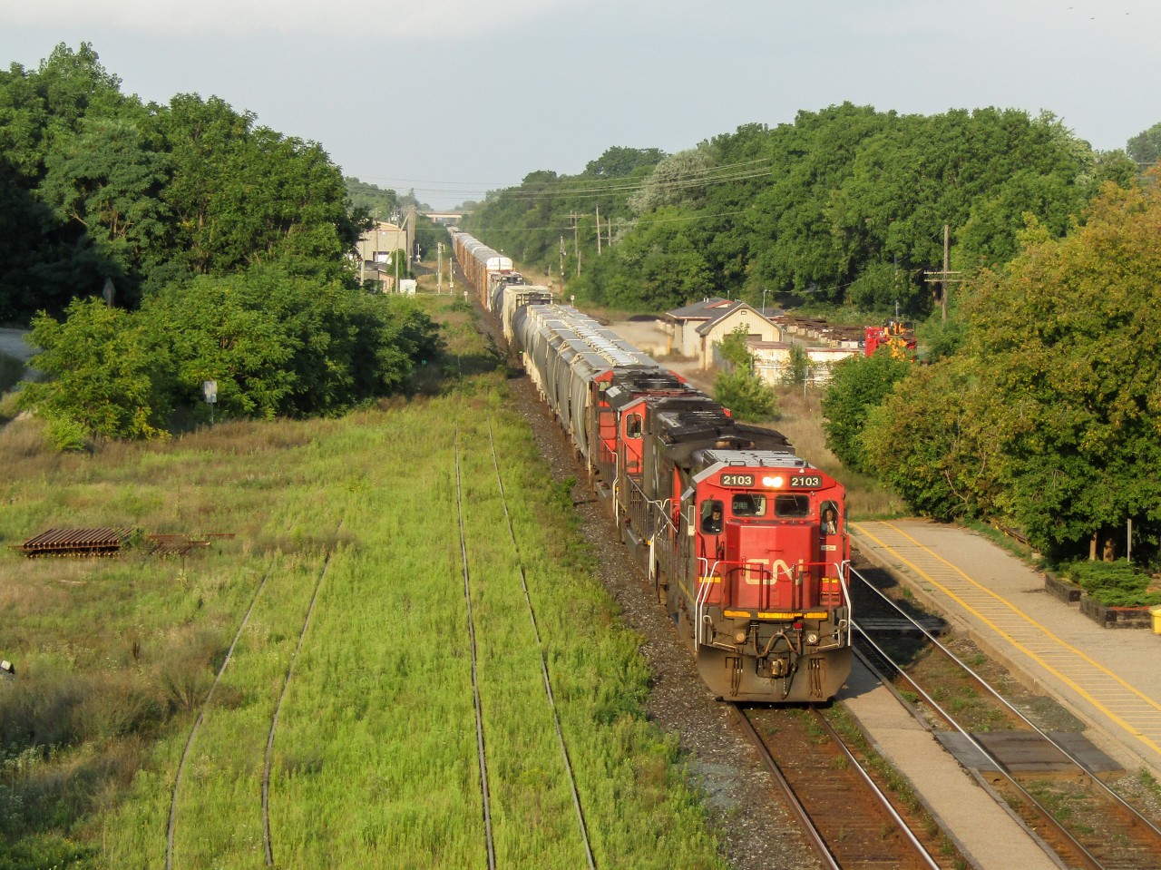 Charging westbound out of an afternoon storm, CN 435 is bathed in evening light coming down the hill towards Woodstock. Leading is veteran C40-8 standard cab 2103, with an SD70I and SD70M-2 trailing. Also noted is a beautiful mechanical bell and a nice horn from a friendly crew!