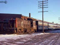 The equipment for trains 160/161 lays over at CN Guelph Junction in siding XW36 on a cold weekend in January, 1975.  160/161 was a Guelph-Toronto and return passenger train, departing Guelph at 0625h, and returning at 1905h.  On this day the train's power is GMD SW1200RS 1240, built by GMD in 1956, would be retired in 1989 and sold to Relco as their 1283, disposition afterwards unknown. The unit was likely painted similar to <a href=http://rrpicturearchives.net/showPicture.aspx?id=5183499>Relco 1282.</a><br><br>Behind the train is the Guelph Twines plant, having been taken over in 1972 after moving to Guelph from Brantford.  The company still operates from this building today, receiving hopper cars from CN approximately 4-6 times per year.  Prior to 1972, the building was the home of the Prestolite-Leland company; a Divison of Eletra of Canada.  The company was a small motor manufacturer from Sarnia, having taken over the business in 1970 from the Wagner-Leland Division of Sangamo company Limited.  All companies produced small motors.  Earlier occupants of building are unknown.