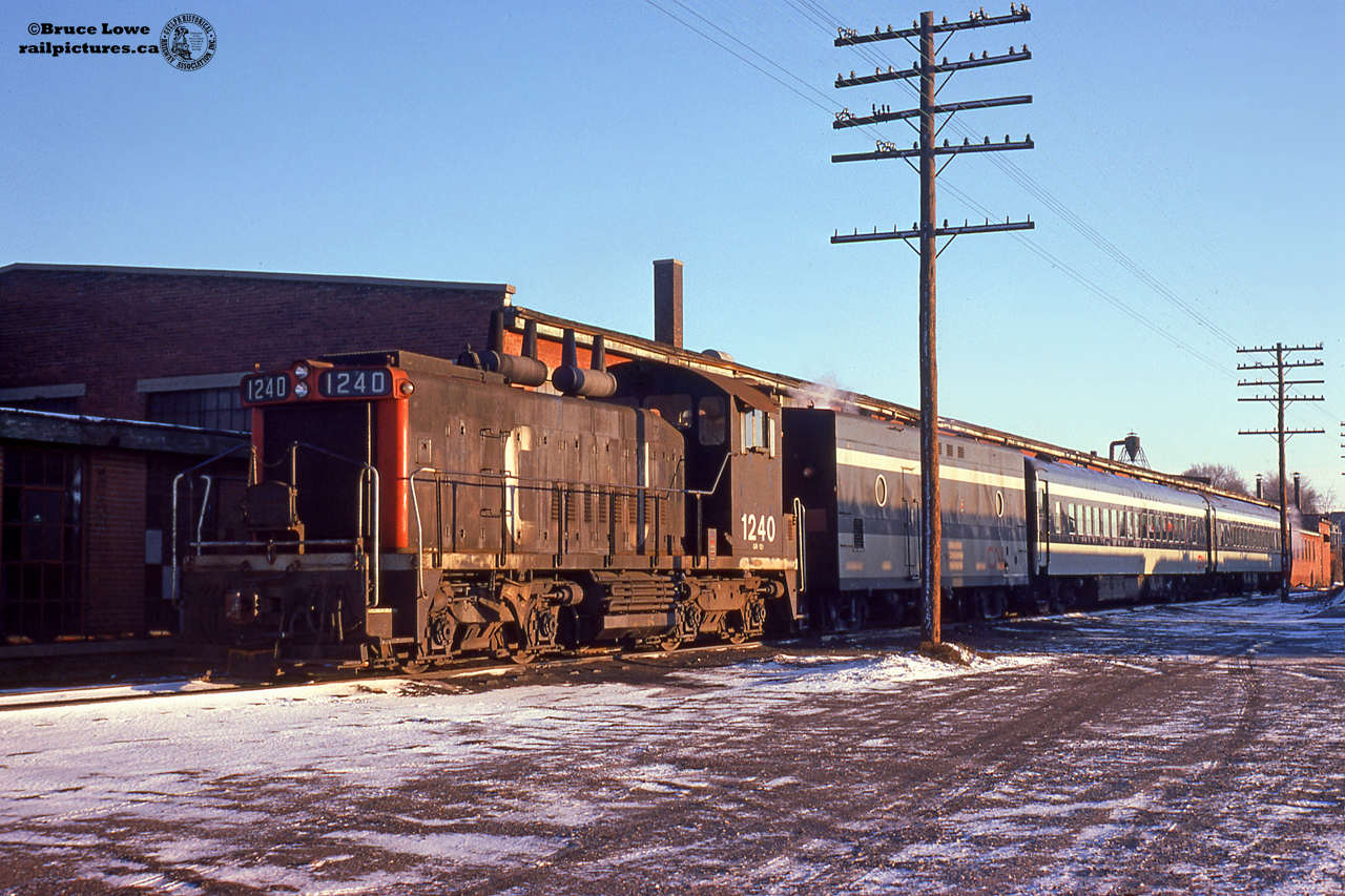 The equipment for trains 160/161 lays over at CN Guelph Junction in siding XW36 on a cold weekend in January, 1975.  160/161 was a Guelph-Toronto and return passenger train, departing Guelph at 0625h, and returning at 1905h.  On this day the train's power is GMD SW1200RS 1240, built by GMD in 1956, would be retired in 1989 and sold to Relco as their 1283, disposition afterwards unknown. The unit was likely painted similar to Relco 1282.Behind the train is the Guelph Twines plant, having been taken over in 1972 after moving to Guelph from Brantford.  The company still operates from this building today, receiving hopper cars from CN approximately 4-6 times per year.  Prior to 1972, the building was the home of the Prestolite-Leland company; a Divison of Eletra of Canada.  The company was a small motor manufacturer from Sarnia, having taken over the business in 1970 from the Wagner-Leland Division of Sangamo company Limited.  All companies produced small motors.  Earlier occupants of building are unknown.