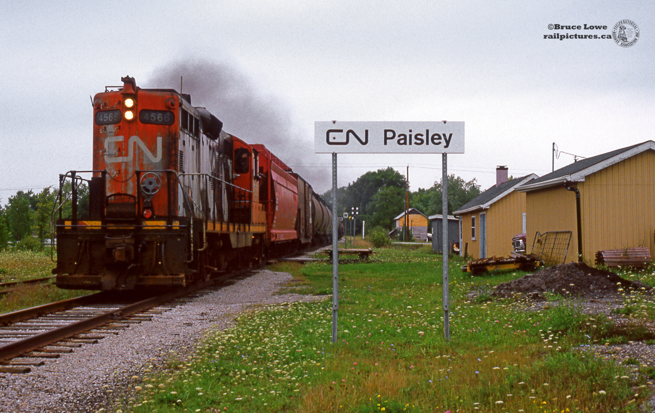 The hogger on extra 4566 opens the throttle to get his train up to track speed after clearing the Teeswater River bridge at Paisley on the Southampton sub. Easy load for the geep with about 9 cars and the van, including a 12-axle depressed centre flatcar returning empty from Bruce Nuclear just ahead of the van.While originally planned in 1856, the Southampton sub would not be completed until December, 1872. During the railway boom of the 19th century, the Canada North-West Railway (C.N.W.Ry.) was incorporated in May, 1856 to build a line from Toronto to Southampton. The line was surveyed by Sanford Fleming (who also surveyed the majority of both the Intercolonial Railway and Canadian Pacific Railway), but no work was completed due to lack of funds and the charter expired in 1861. In 1864 another attempt was made, now under the name of the Wellington, Grey & Bruce Railway with the intent of building from the Great Western Railway at Guelph (today CN Guelph Junction) north west to Southampton. Construction of the Provincial gauge line began in June, 1867 from Fergus, working west to Elora and north west to Alma. 1869 saw the Great Western Railway take over the physical operations of the W.G.& B. Ry. continuing construction south to Guelph in 1870 and north towards Palmerston. The G.W.R. sought an amendment to the original charter in 1870 to change the line from the Provincial gauge of 5ft - 6in to standard gauge, and to allow future lease of the line to the G.W.R. This was granted and construction continued under the new gauge and lease.1871 saw the line open for service to Palmerston and Harriston while crews worked northward. Paisley was ready for service by June, 1872 and finally Southampton in December of that year. Starting in December, 1871, crews were working south west from Palmerston on a branch line to Kincardine via Listowel; eventually part of the CNR Newton Sub, and the Kincardine Sub. This portion would be ready for service in November, 1873, but would see no trains until December, 1874 due to costs owing to the contractor. Though there were further plans for expansion to Owen Sound and Durham, the lack of funds kept the line from pressing on, and the fact that other companies (Toronto, Grey & Bruce Rwy.) were building that way. Great Western Railway would take over operation of the trains in 1873, which soon after was merged with the Grand Trunk in 1882. Official amalgamation of the W.G.& B. into G.T.R. would take place in 1893, eliminating the Wellington, Grey & Bruce name entirely. 1923 saw the bankruptcy of the Grand Trunk and the creation of Canadian National Railways, who would operate the lines in the 1980's and early '90's. Passenger service ended November 1, 1970, one year after Paisley's station closed on October 24, 1969. Passengers would purchase their tickets onboard the Dayliner for that final year. 1970 saw the beginning of slightly increased freight service on the line with saw the construction of the 11.4 mile Douglas Point spur from Port Elgin south to the Heavy Water Plant at the Bruce nuclear Generating Station. The spur was used for unit trains of bunker C oil from Montreal (briefly) and later Sarnia allowing the plant to create steam for the early CANDU reactors. The requirement of these trains of 60 cars or so led to the Fergus, Owen Sound (Palmerston - Harriston), Newton, and Southampton subs receiving numerous upgrades in 1969 to rail and ties for the heavier trains. After about a decade the market for the CANDU reactors never took off and a generator was able to provide the reactors with enough heavy water, leading to the heavy water plant being shut down in 1984. With the lifeblood of the line gone, CNR applied to abandon the Southampton sub from Harriston to Douglas Point in 1988 (Port Elgin to Southampton had been abandoned in 1983.) The request was granted, and the line was removed during 1989.CN GP9 4566 was built by GMD in 1957 and rebuilt to CN 7049 in 1991. The unit would be off the CN roster in 2009.