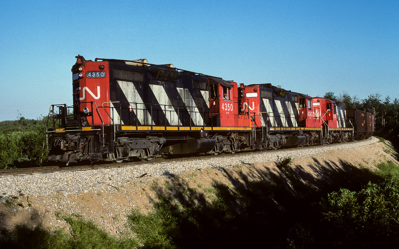Gliding downgrade from the town of Redwater, empty sulphur buggies are headed north to be refilled. Once the units have passed over the trestle, which is immediately to photo left, the throttle will be upped a few notches to climb the hill to Kerensky. At Kerensky, they will leave the Coronado Sub., taking the connecting track to the Lac La Biche Sub. and the distant destination of Waterways. It will return 2 evenings later with nearly 50 loads and the 4602 added in for extra help.