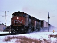 On a typical Northern Ontario winter morning, train 221, with typical power for that time period, bounces over Regional Road 80 and the south switch at Hanmer, Ontario at speed.  The short Hanmer siding was used occasionally for storage, was never used as a passing track after CTC was installed, and has since been removed.  Power for the 103 car train was 9526, 9596, and 9537. 