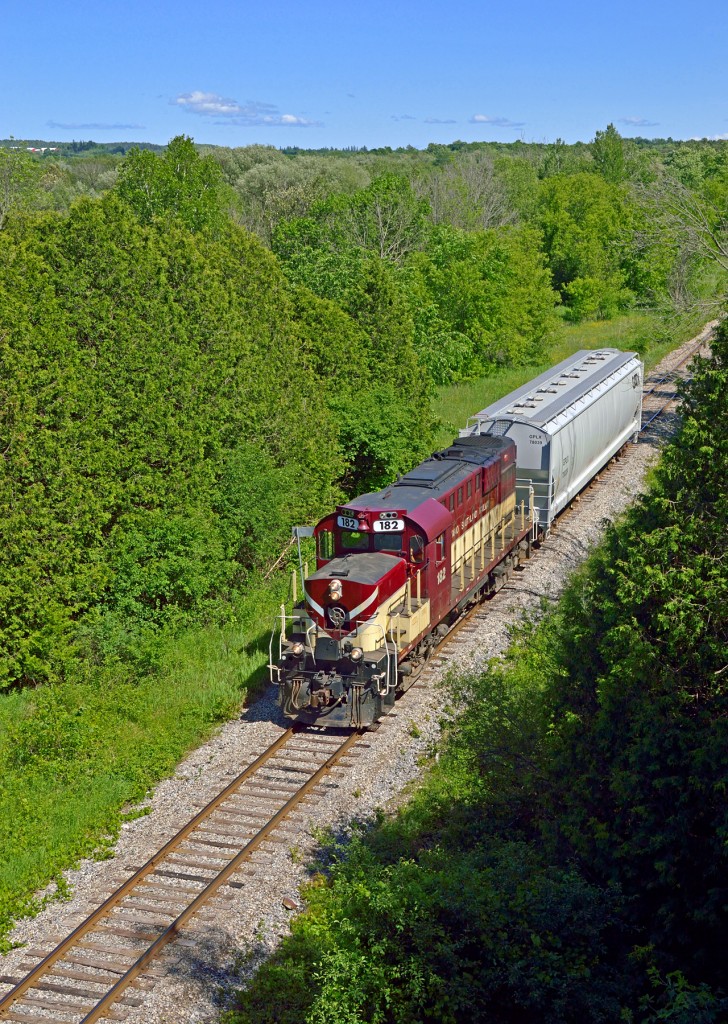 With a lone car for PDI Elizabeth in tow, OSR's 1400 job approaches Guelph at a place once known as Speedwell.  Located at mile 29.6 on the Goderich sub (page 9), Speedwell was a flag stop for the CPR, the Toronto Suburban Railway, and the Guelph Radial Railway; the latter two being electric lines.Built under the direction of Sir William Mackenzie and Sir Donald Mann (of Canadian Northern Railway fame), the Toronto Suburban Railway's Guelph Line ran 49.4 miles from Toronto at St. Clair and Keele Street through towns including Cooksville, Meadowvale, Georgetown, Eden Mills, and Guelph.  There was 100 stops along the line, many likely at farmers' crossings lacking any formal station.  Mackenzie & Mann's aim of building quality lines at low cost saw the line built with 60lb rails, weaving west through many curves and over large bridges including the 711-foot long Humber River bridge and a 315 foot wooden trestle across the Credit River near Norval, until reaching the Guelph terminus at the Grand Trunk Railway station on Carden Street via a connection with the Guelph Radial Railway at Dundas Street and Bay Street; now renamed Gordon Street and James Street East.  A storefront on Carden Street (behind train here) across from GTR's station provided TSR customers with a place to purchase tickets.  Being a longer interurban line, the TSR cars on the Guelph Line were larger, constructed by the Preston Car and Coach Co, described as a "68-seat affair and nicely appointed with cherry wood finish throughout, comfortable green, plush, upholstered, high-backed seats with headrests, footrests and polished bronze handles on the aisle sides."  The first car over the line arrived in Guelph on Thursday, August 12, 1917 with management and foreman aboard, declaring on arrival, that the line would open to the public that Saturday, August 14.  The intended destination of the Guelph Line after surveying during 1911 was originally Berlin, now Kitchener, however restrictions and costs during WWI resulted in the destination of Guelph.  Three hydro substations were built to supply the line with 1,500 volt D.C. but only 2 (Islington, Georgetown) were ever used.  The third, located in Guelph on Bay Street was built for the Kitchener end of the line, but was not needed after cutbacks.  The building is now a private residence.  In September, 1918, Mackenzie and Mann amalgamated the TSR with the Canadian Northern Railway ultimately becoming the Toronto Suburban Division of the Canadian National Electric Railways on December 17, 1923.  With the rise in ownership of the automobile, faster schedules provided by both Canadian National and Canadian Pacific Railways, and reduced service due to the Great Depression, the CNR chose to discontinue service on the Toronto Suburban Railway Division by allowing it to enter receivership.  The last day of service was August 15, 1931 and the line was dismantled in late 1935 after the debts were paid.  Today, a short stretch of the line has been rebuilt in the form of the Halton County Radial Railway on Guelph Line in Eden Mills.  Just up the line from OSR here, the TSR crossed the CPR at a diamond before passing under Victoria Road.  PDI's Bulk Liquid facility is now just out of frame to the right across the river.The Guelph Railway Company was chartered in 1894 by businessman George Sleeman of the Silvercreek Brewery to provide his employees, and the City of Guelph, with an easier way to get to work.  Construction began in early 1895 with service beginning on September 17, 1895 centered around St. George's Square.  Freight service would begin in 1900.  The line ran throughout Guelph's streets under different owners; Sleeman, 1895-1902; Bank of Montreal and Trader's Bank of Canada, 1902-1903, renamed Guelph Radial Railway; City of Guelph, 1903-1921: Ontario Hydro, 1921-1936.  Under the latter the name was changed to Ontario Hydro Electric Railways - Guelph District.  Beginning in 1926 buses began service on many routes to supplement the cars, or replace the streetcars where track conditions were poor.  Ontario Hydro attempted to sell the line back to the city, but they wanted no part in it.  Streetcar service would end in Guelph on September 30, 1937.  Electric freight service continued until May 26, 1939; the same year the company, now all buses, would be renamed Guelph Transportation Commission.  Guelph Radial service to Speedwell was provided on Sundays only when the TSR traffic would be light.  The station was accessed over the TSR line from Dundas/Bay Streets east to the station.  The area was used by many for for fishing, picnics, or visiting people at the Ontario Reformatory. A complete Inventory of Shop Tools & Car Equipment of Guelph Radial Railway from December 1920 can be found here.Just across the river from my photo lies the former Ontario Reformatory/Guelph Correctional Centre Prison Farm, in use from 1909 - 2002, the farm shutting down in 1972.  The prison was constructed of stone quarried onsite by the inmates and the quarry expanded to provide material to other construction projects.  The prison was serviced by the CPR on a spur running across the river to deliver coal and a switchback to lift cars of stone and gravel from the quarry loader.  Inside the quarry was a narrow gauge railway built on 25lb. rail temporary tracks that could be moved where they were needed.  The locomotive was a 12 ton H. K. Porter 0-4-0 named 'Liz' built in 1911 and operated by the inmates.  1917-1920 saw the reformatory used as the Speedwell Convalescent Hospital for returning veterans, helping to heal them and aid in their return to civil life.  This was short-lived however as the conditions inside the hospital worsened with a lack of upkeep brought on by embezzlement, and the decision was made to revert the hospital to a prison.Speedwell, a place at one time having a class 1 railway, an electric railway served by two operators, and a narrow gauge railway all within 1/4 miles or less of each other.