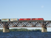 CP 253 has a pair of red SD70ACU's (CP 7003 & CP 7053) as it crosses the St. Lawrence River. The moon is still visible on this clear but chilly morning.