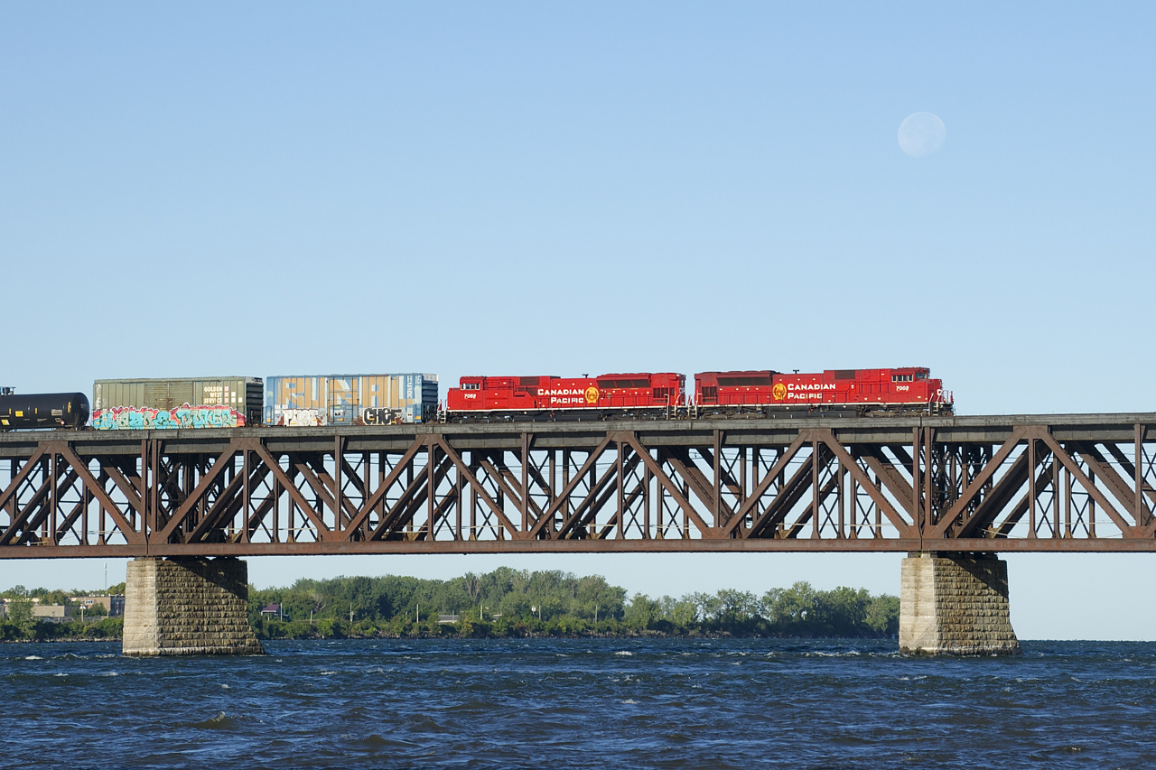 CP 253 has a pair of red SD70ACU's (CP 7003 & CP 7053) as it crosses the St. Lawrence River. The moon is still visible on this clear but chilly morning.