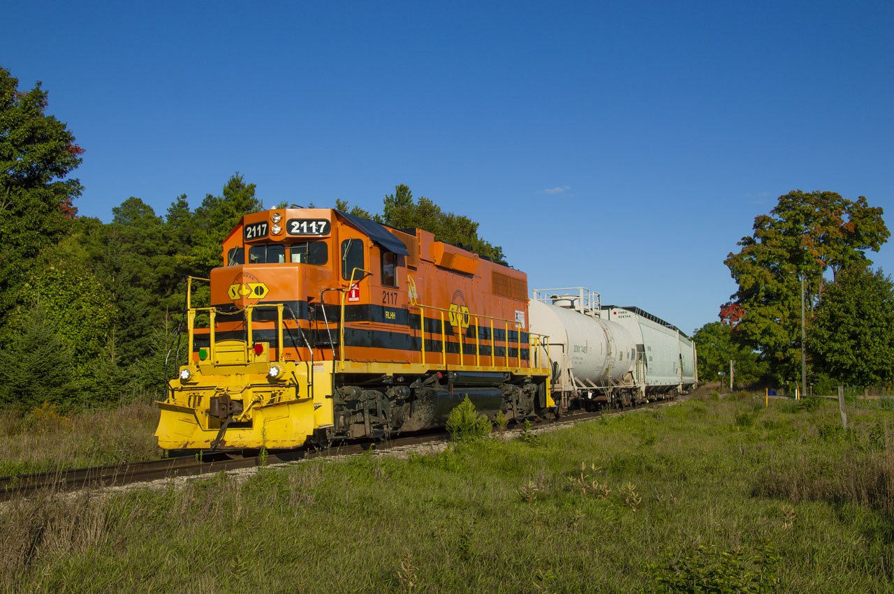 GEXR 583 shoves back across Carter Road into the north siding at Arkell in the evening sun after lifting a few cars for PDI Elizabeth.  The crew would tie back onto their train and proceed northward to Guelph for the evening's work.Carter Road (mile 27.55) marks the approximate boundary between the communities of Arkell and Farnham; a community that began years ago, but failed to fully materialize.  Farnham, originally Farnham Plains, was founded by John Arkell (1802-1881) who immigrated to the Puslinch area in 1831 from Kempsford, South Gloucestershire, England.  He would begin settling 1800 acres about 3/4 of a mile west of today's Arkell with his cousin Thomas Arkell.  An Anglican Church was built in 1854 beside the cemetery as the main component of the community, however few people remained in Farnham as Arkell prospered, likely in part to the coming of the Guelph Junction Railway in 1888.  The church building was moved to Arkell in 1901 as few people remained in Farnham; only the cemetery and Thomas Arkell's house remain today.The Canadian Pacific's Arkell station was built in 1888 and served the community until passenger service ceased on Saturday, August 4, 1962.  Prior to this passenger service was typically operated using a Battery Car, often with CPR 9002, nicknamed "Old Sparky" by residents along the line.  Sparky would be replaced by CPR 9004, a gas-electric doodlebug in the 1940s until 1958 when steam powered mixed trains would take over the passenger service.  Arkell station would be sold in 1963 to the Trustees of the Farnham Cemetery (still in use today) for use as a tool shed, but was later demolished and a replica was built in it's place.