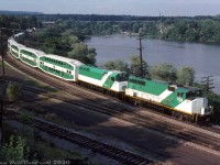 After finishing their evening run to Hamilton (James Street) station, an 8-car GO train departs eastbound, passing Burlington Bay while deadheading back to Willowbrook Yard in Mimico (Toronto). GO GP40-2W 700 leads up front on the approach to Bayview Junction, with GP40-2W 708 and F40PH 511 seen bringing up the rear through Hamilton Junction. Three locomotives and eight bilevels might seem a bit overpowered, but at the time GO Transit's six new F40PH units (510-515) were only a month or two old, so 511 could be doing break-in or test runs before being released on its own (it would also be the only unit here able to provide HEP to the bilevels).<br><br><i>Reg Button photo, Dan Dell'Unto collection slide.</i>